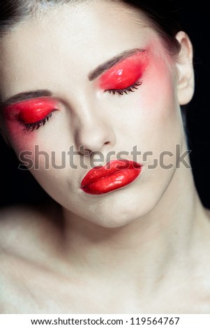 Portrait of a beautiful sexy brunette girl with red lips and red eyes