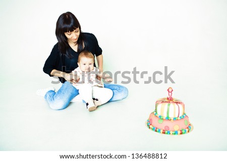 mother and daughter sitting on the floor with cake isolated on white