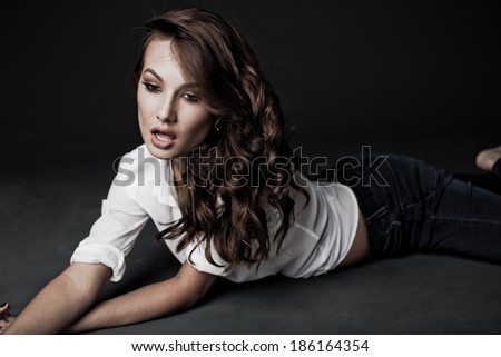 Lovely woman in white blouse and blue jeans lying on the floor