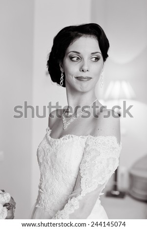Gorgeous bride in wedding dress in luxury interior with diamond jewelry posing at home and waiting for groom. Romantic rich happy girl in bridal dress smiling have final preparation for wedding