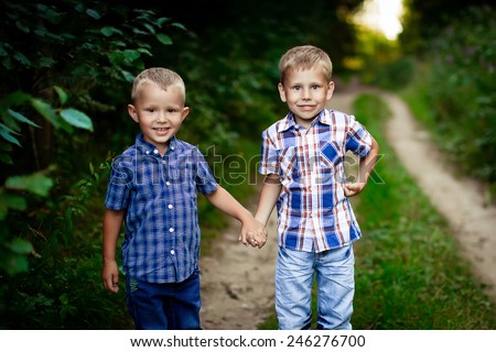 Two brothers hugging each other outdoor, smiling and laughing