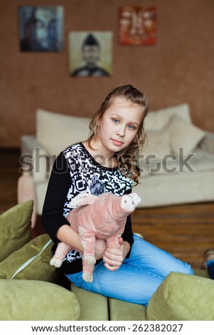 Girl sitting on the couch with a pig on his hands
