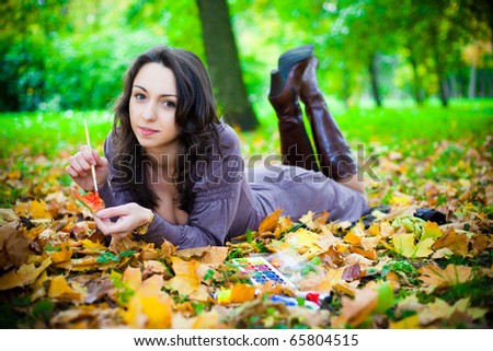 girl lies on the leaves, and draws on the leaves