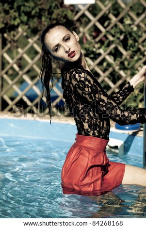 Fashion woman posing poolside in red skirt
