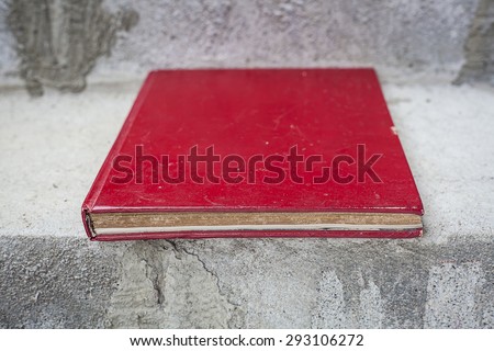 Old red book placed on concrete stairs. You can design and add text or products.