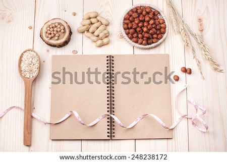 Overhead view of a notebook, nuts and oat, wrapped in measure tape in diet , weight loss and healthy nutrition concept  lying   On wooden table