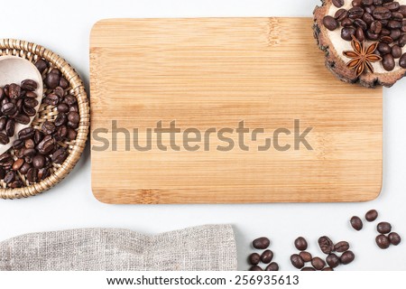 Coffee beans in wooden spoon, lying on sackcloth with wooden stand with star anise with place for text on wooben desk