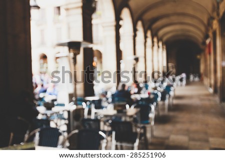 Street cafe in Barselona with square metal table and wicker chairs on the background of blurred street with people