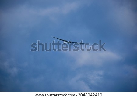 Ein Segelflugzeug fliegt am blauen Himmel mit dramitschen Wolken Stock foto © 