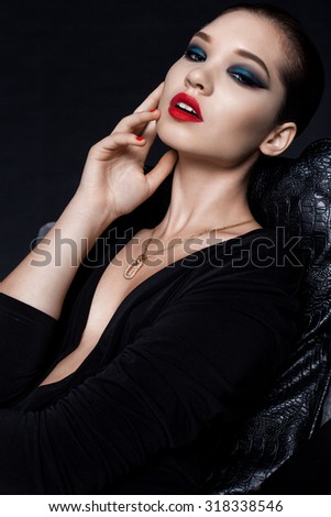 Portrait of a beautiful young girl Europeans, with a bright evening make-up, expensive jewelry made of precious metals and stones in a chic black long dress with a neckline.