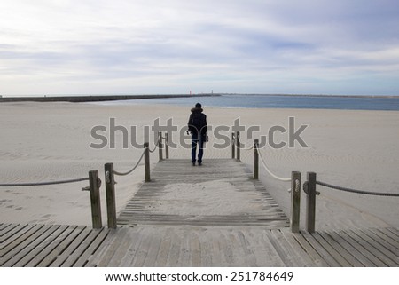 Isolated male figure on the edge of the bridge on the beach. looking at the ocean
