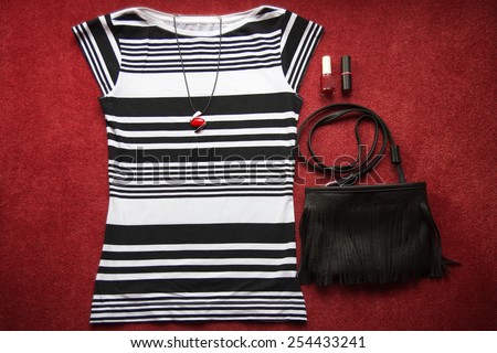 Fashion outfit. striped shirt, pendant, handbag, lipstick and nail polish.