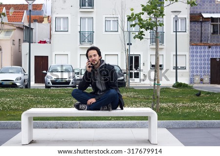 Young man talking on the phone, sitting on the bench.