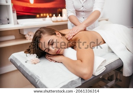 Young woman get massage in spa salon at luxury spa room. Customer receiving shoulders massage on spa bed that make her relieve stressed Oriental massage therapist massage customer body. She get relax