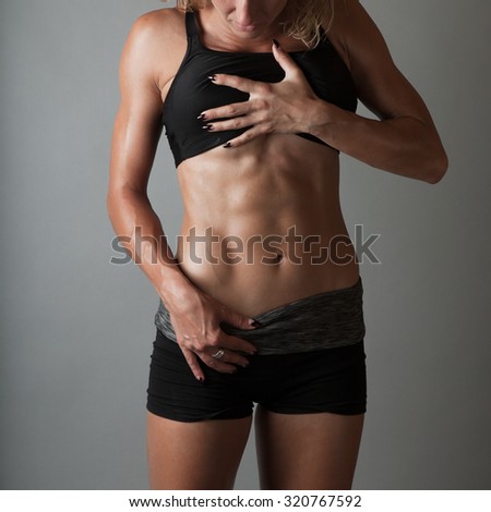 Beautiful super fit young woman showing off her perfect muscular ripped abs. Fitness model. Perfect Slim Body. Studio shot