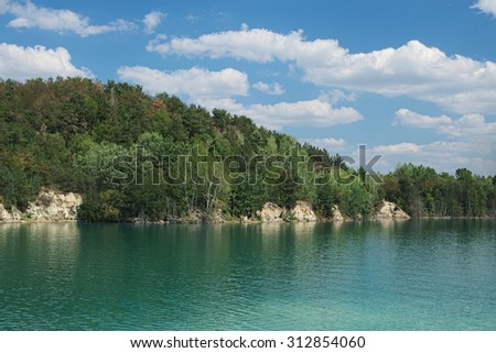 Lake with green water and hill with trees.