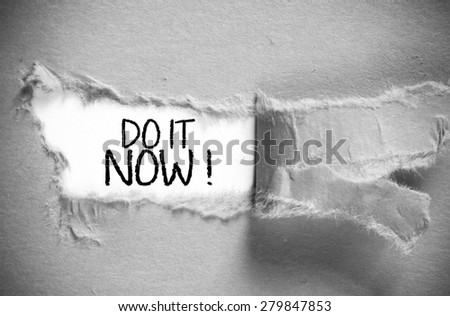The word Do it Now appearing behind torn paper