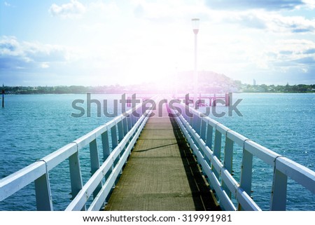 Concrete pier going to horizon over blue water. Selective focus