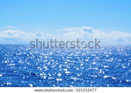 Out of focus seascape with sparkling water under blue sky. Abstract background