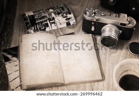 Artwork in retro style, old-fashioned camera, opened book, empty cup of coffee