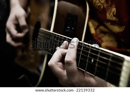 A close up of a guitarists hands playing acoustic guitar. Jazz, rock, classical concert. Narrow depth of field.