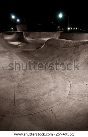 A skate park at night under lights with half pipe in the background