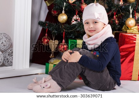 cheerful happy girl at a Christmas tree in a cap , scarf and mittens