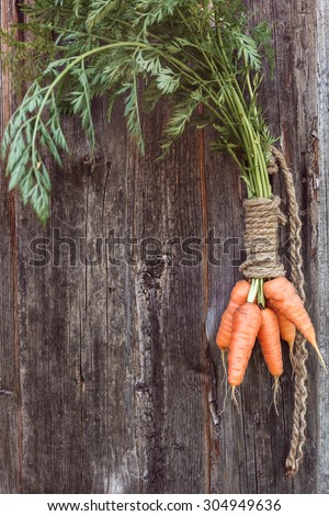 Bunch of fresh carrots with green leaves on a wooden background a place for inscription