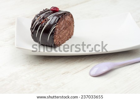 Chocolate cake with chocolate icing on white plate. Shot indoor using artificial light