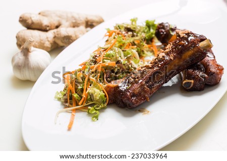Lamb ribs with sweet sauce with salad dressing on a white plate