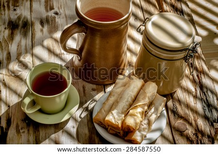 spring roll on a plate on wooden table under afternoon sunlight with shadow