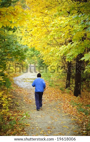 Man jogging towards end of woodland trail in Fall
