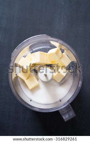 Butter and sugar in food processor bowl. Selective focus