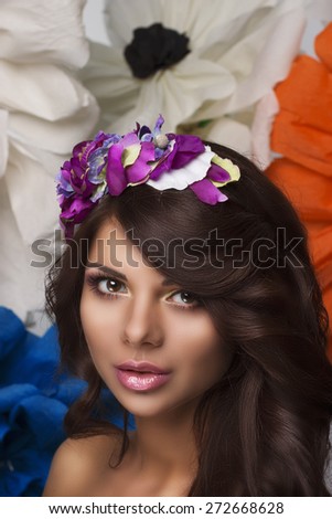 Beauty close up portrait make up of women with a wreath of flowers in her hair and big colorful flowers on background