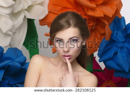 Beauty women portrait holding hair near face and big colorful flowers on background