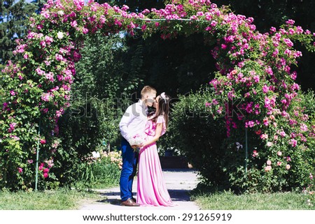 The young bride in a beautiful dress embraces groom at a wedding with a bouquet of flowers. Newlyweds smile at each other