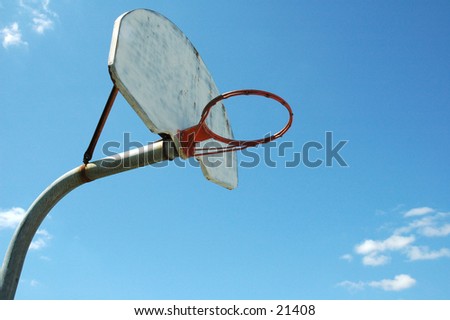 Old, well-worn school-ground basketball hoop (without net) against a sunny, bright, blue sky.