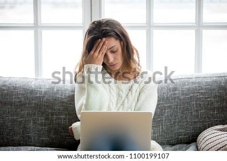 Frustrated sad woman feeling tired worried about problem sitting on sofa with laptop, stressed depressed girl troubled with reading bad news online, email notification about debt or negative message Stock foto © 