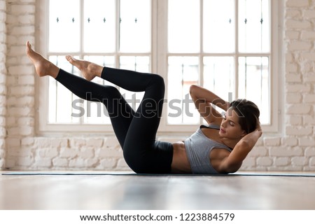 Young sporty woman practicing, doing crisscross exercise, bicycle crunches pose, working out, wearing sportswear, black pants and top, indoor full length, white sport studio Сток-фото © 