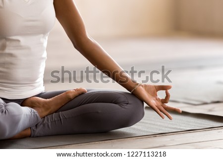 Yogi black woman practicing yoga lesson, breathing, meditating, doing Ardha Padmasana exercise, Half Lotus pose with mudra gesture, working out, indoor close up. Well being, wellness concept Foto stock © 