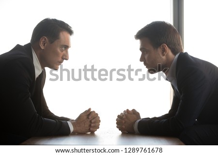 Two confident businessmen with clasped hands look at each other sitting opposite as rivalry confrontation concept, business opponents competitors politicians debate, difficult negotiations, side view Photo stock © 