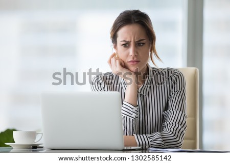 Confused businesswoman annoyed by online problem, spam email or fake internet news looking at laptop, female office worker feeling shocked about stuck computer, bewildered by scam message or virus Stock foto © 