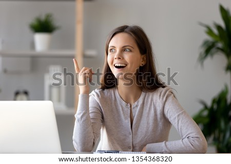 Young happy woman sitting at desk near laptop gesturing with hand make finger up, feels excited with good idea reach inspiration motivation, found solution for success at work or study, eureka concept 商業照片 © 