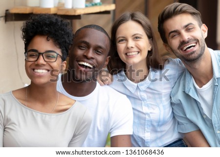 Photo of Happy multicultural friends group looking at camera, young multiracial people laugh having fun posing together, multiethnic friendship concept, diverse african and caucasian students reunion portrait