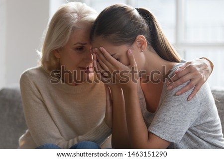 Worried aged mother embracing comforting grown up daughter with broken heart family sit on sofa, elderly mom soothe crying adult child, divorce or miscarriage, share problem with someone close concept