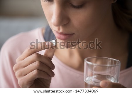 Close up cropped image millennial mixed race girl holding pill and glass of fresh water, taking medicine from head ache, stomach pain or taking vitamins, sedation meds, healthcare concept Imagine de stoc © 
