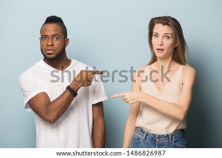 Stressed multicultural young man and woman isolated on blue studio background point finger at each other, surprised frustrated african American male and Caucasian female blame accuse one another Stockfoto © 