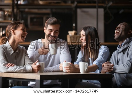 Photo of Happy multiracial friends group laugh drink tea in cafe, diverse young students talk enjoy coffee at coffeehouse meeting, multicultural people sit at table having fun together multi-ethnic friendship
