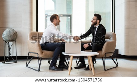Horizontal view european and arabian businessmen in formal wear accomplish meeting shaking hands feels satisfied after negotiations, HR manager greeting applicant before job interview process concept