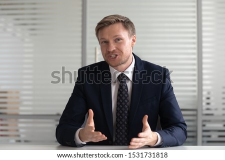 Portrait confident businessman coach wearing suit looking at camera and talking, making video call, mentor coach tutor recording webinar, online course, hr manager holding distance job interview